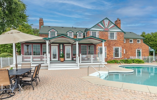 rear view of house featuring a fenced in pool and a patio area