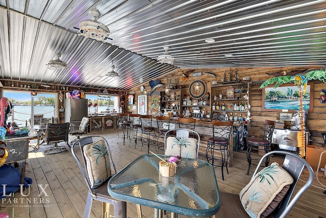 dining space featuring hardwood / wood-style flooring, wood walls, lofted ceiling, and a healthy amount of sunlight