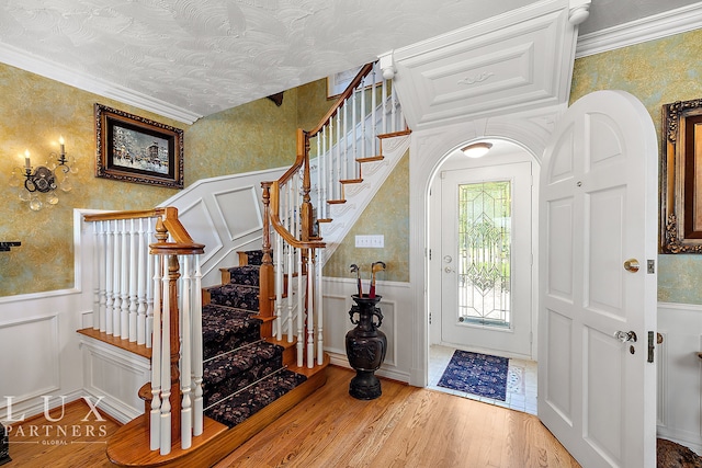 foyer with wood-type flooring, ornamental molding, and a textured ceiling