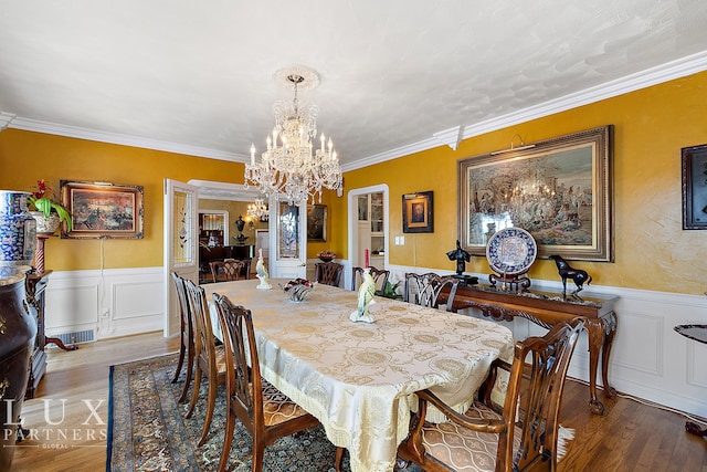 dining room featuring hardwood / wood-style flooring, crown molding, and a chandelier