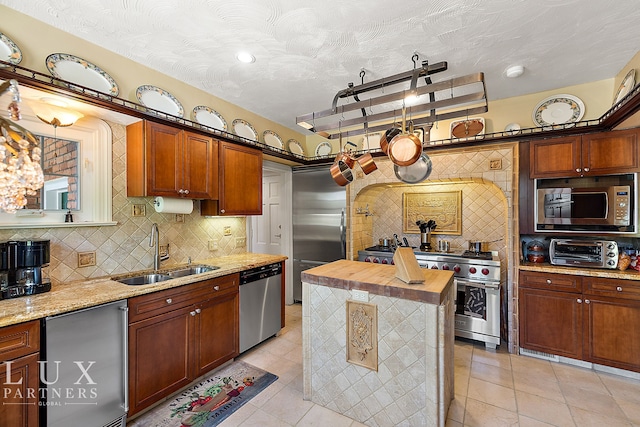 kitchen featuring built in appliances, a center island, wooden counters, sink, and backsplash