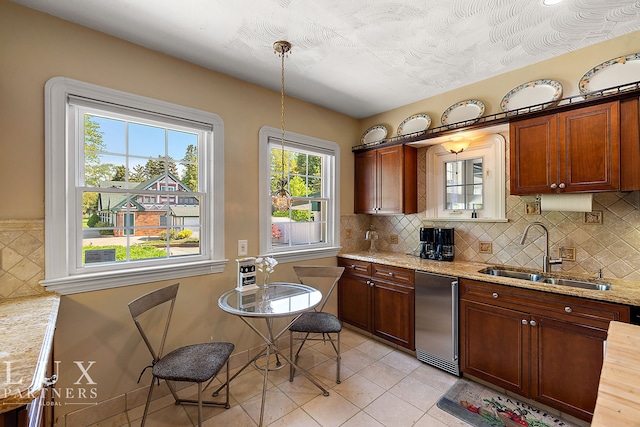 kitchen featuring sink, light stone counters, pendant lighting, and light tile patterned flooring