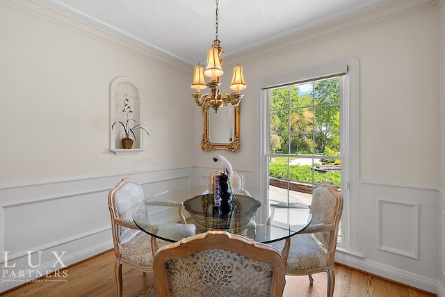 dining area featuring light hardwood / wood-style floors, ornamental molding, and a chandelier