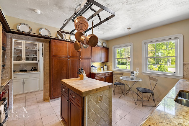 kitchen with light tile patterned flooring, decorative backsplash, a center island, and hanging light fixtures