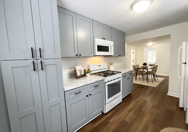 kitchen with dark hardwood / wood-style floors, white appliances, gray cabinets, and a textured ceiling