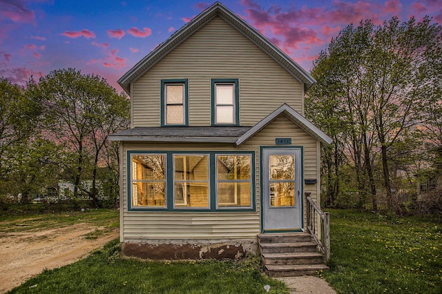 back house at dusk featuring a yard