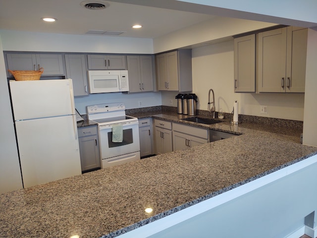 kitchen featuring kitchen peninsula, sink, white appliances, and dark stone countertops