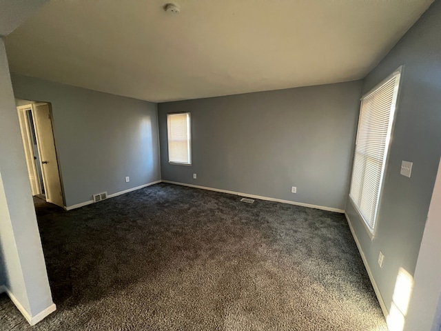 spare room with dark carpet