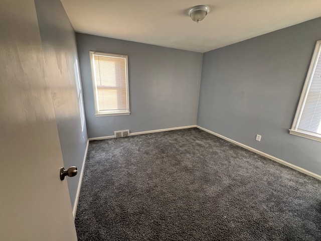 unfurnished room with dark colored carpet