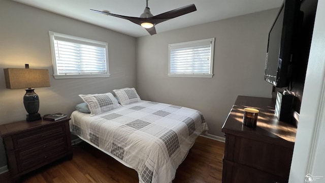 bedroom featuring ceiling fan, multiple windows, and dark hardwood / wood-style flooring