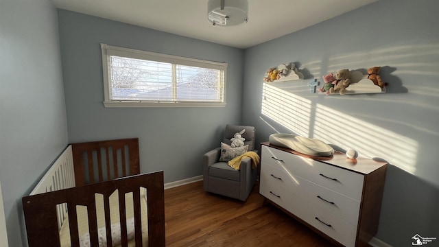 bedroom with dark hardwood / wood-style flooring and a crib