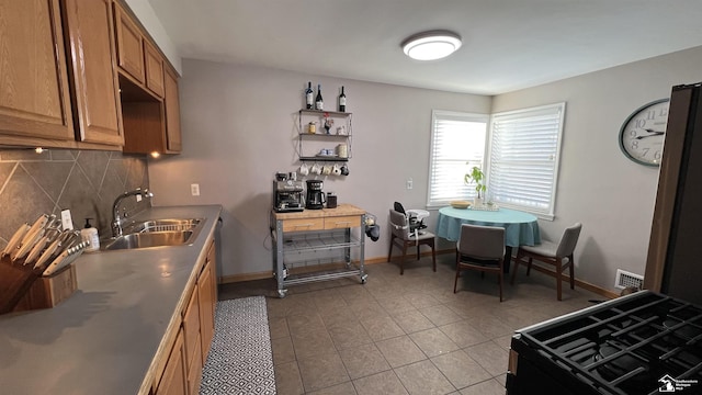 kitchen with decorative backsplash, sink, and light tile patterned flooring