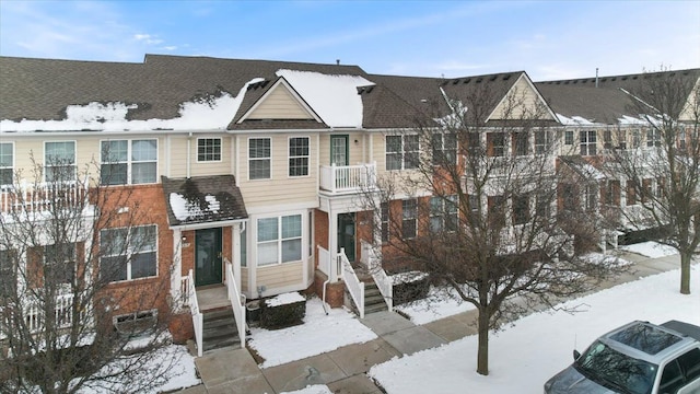 view of front of home with a shingled roof and brick siding