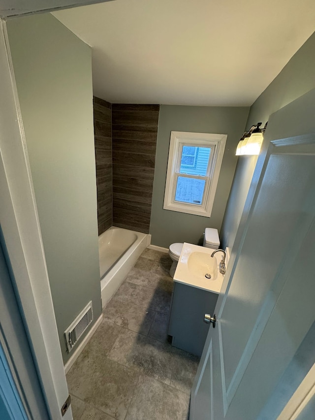 full bathroom featuring vanity, tiled shower / bath, and toilet