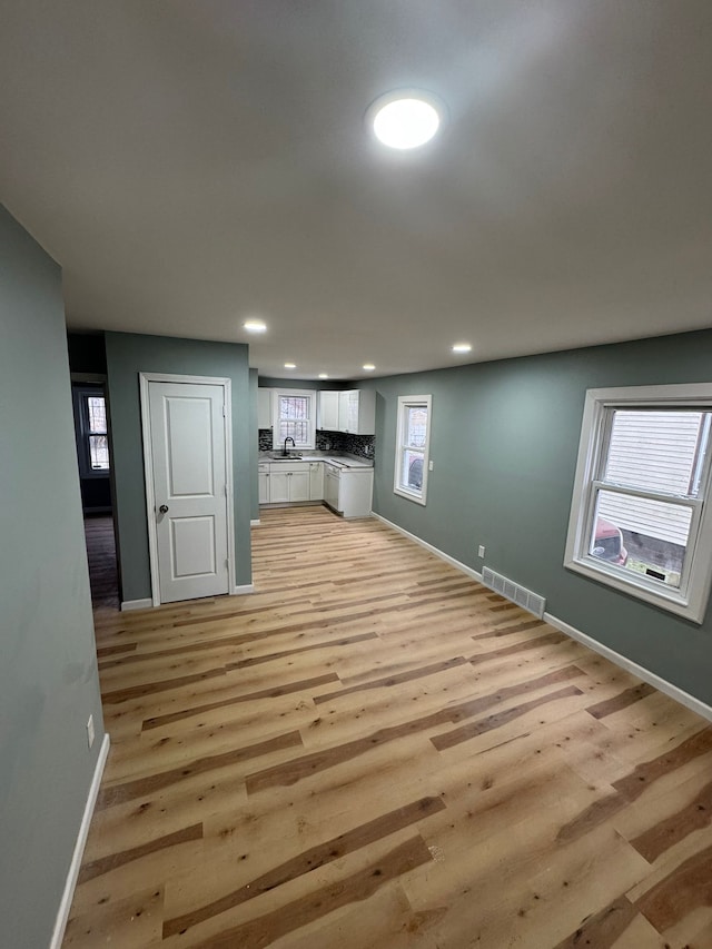 unfurnished living room featuring sink and light hardwood / wood-style floors