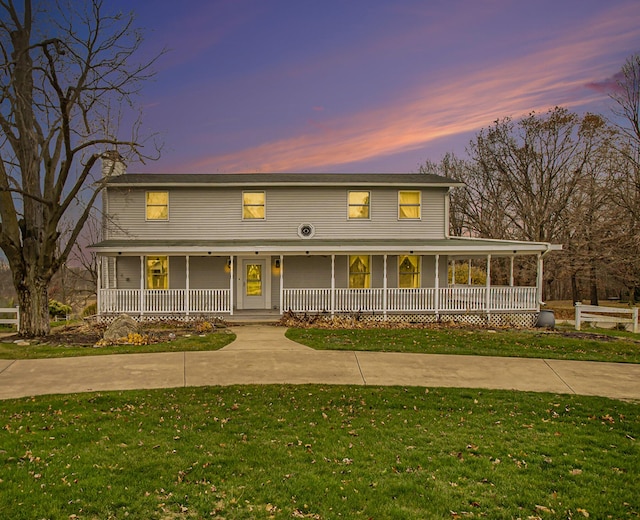 country-style home with covered porch and a yard