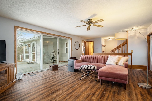 living room with a textured ceiling, ceiling fan, and dark hardwood / wood-style floors