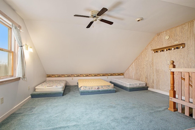 unfurnished room featuring ceiling fan, vaulted ceiling, carpet floors, and wood walls