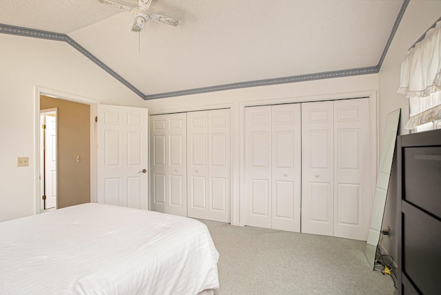 carpeted bedroom with ceiling fan, lofted ceiling, and two closets