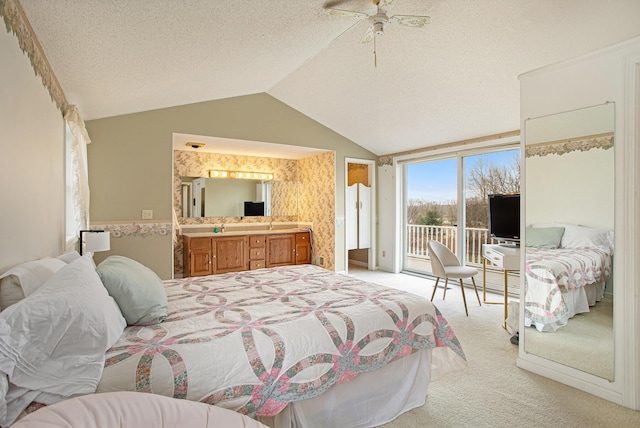 carpeted bedroom featuring a textured ceiling, lofted ceiling, connected bathroom, access to outside, and ceiling fan