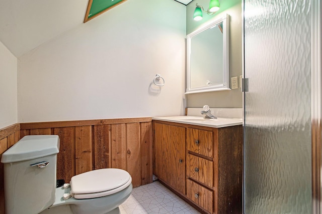 bathroom featuring toilet, vanity, tile patterned flooring, vaulted ceiling, and wood walls