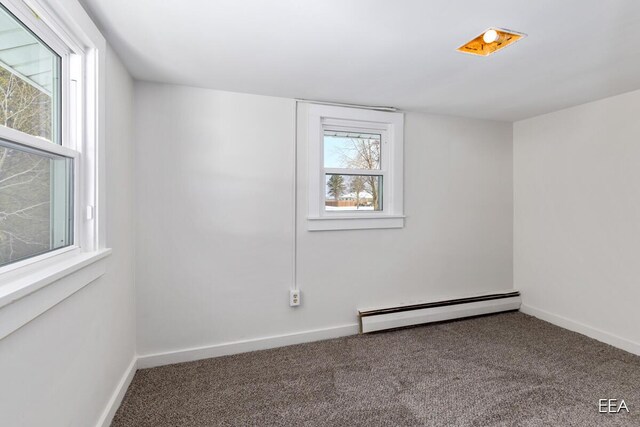 carpeted empty room with a baseboard heating unit