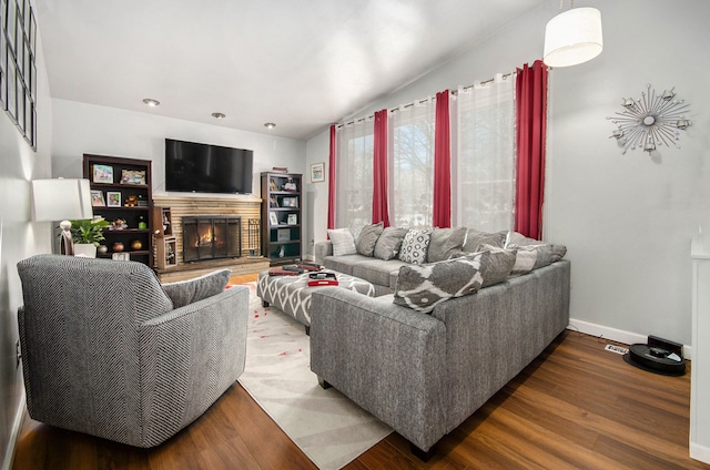 living room with wood-type flooring and a stone fireplace