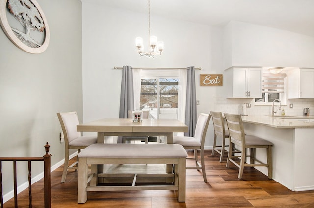 dining room featuring high vaulted ceiling, dark hardwood / wood-style floors, sink, and a chandelier