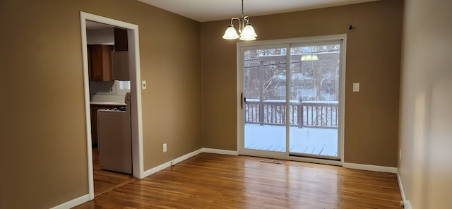 unfurnished dining area featuring an inviting chandelier, hardwood / wood-style flooring, and washer / clothes dryer