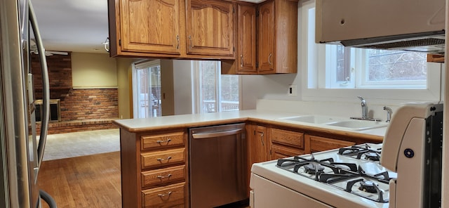 kitchen with a wealth of natural light, appliances with stainless steel finishes, kitchen peninsula, and sink