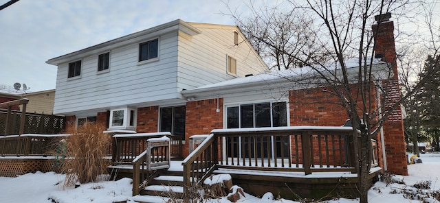 snow covered house with a wooden deck