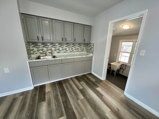 bar featuring sink, dark hardwood / wood-style floors, gray cabinetry, and tasteful backsplash