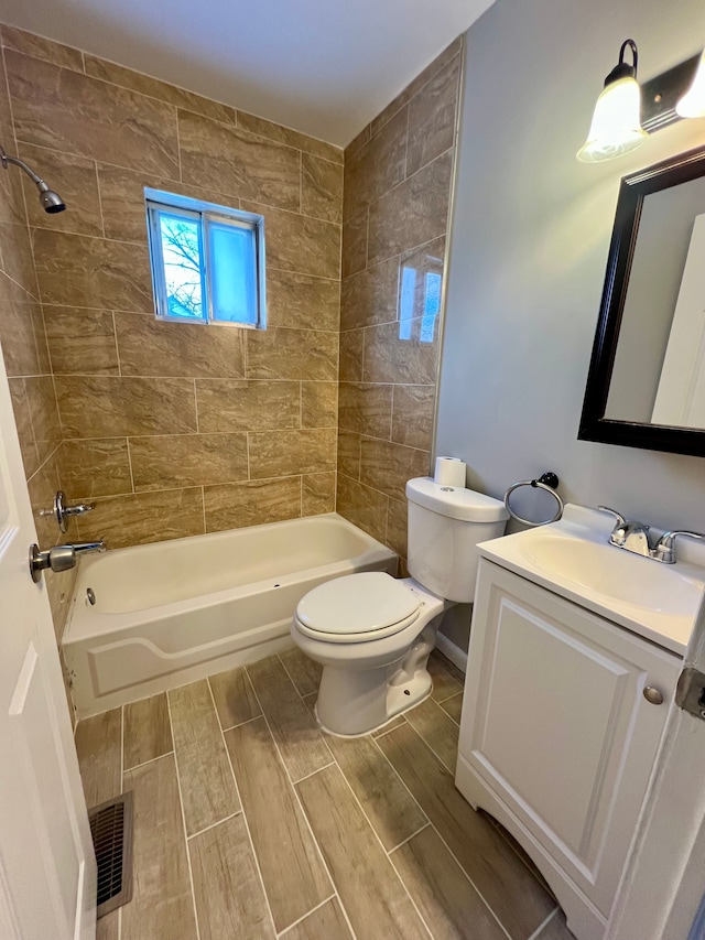 full bathroom featuring toilet, tiled shower / bath, and vanity