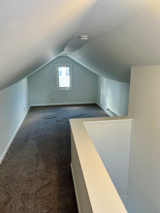 additional living space featuring a baseboard radiator, vaulted ceiling, and dark carpet