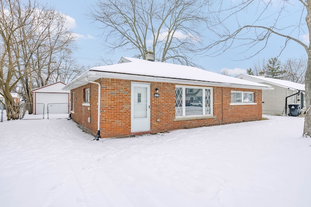 snow covered house featuring a garage and an outdoor structure