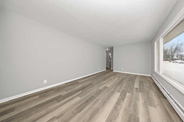 unfurnished room with a baseboard heating unit and wood-type flooring