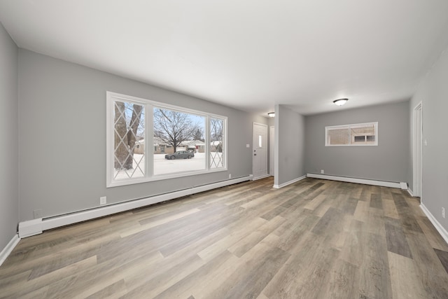 unfurnished living room featuring a baseboard heating unit and light hardwood / wood-style floors