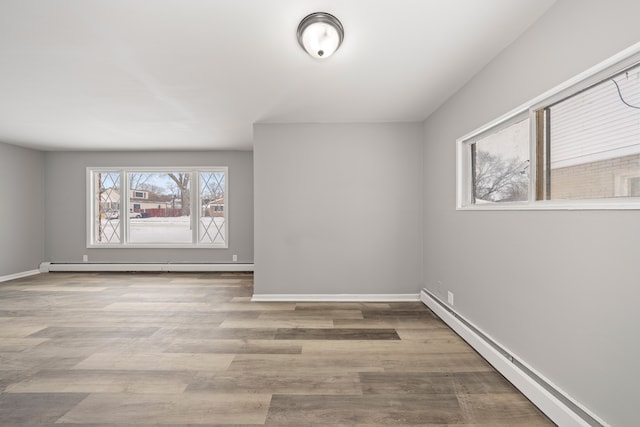 empty room featuring wood-type flooring and a baseboard radiator