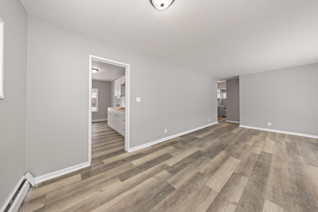 unfurnished room with light wood-type flooring and a baseboard radiator