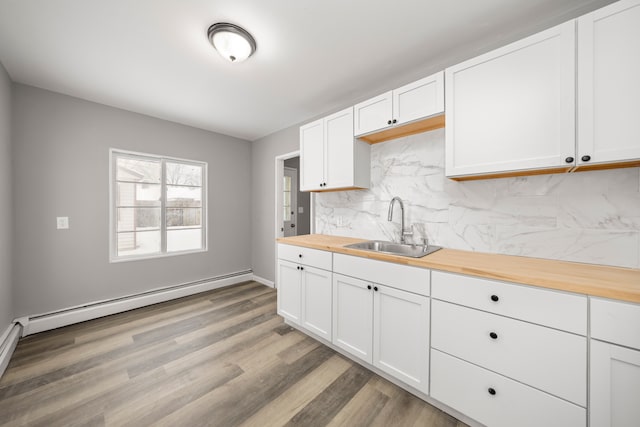 kitchen featuring white cabinets, wood counters, a baseboard heating unit, tasteful backsplash, and sink