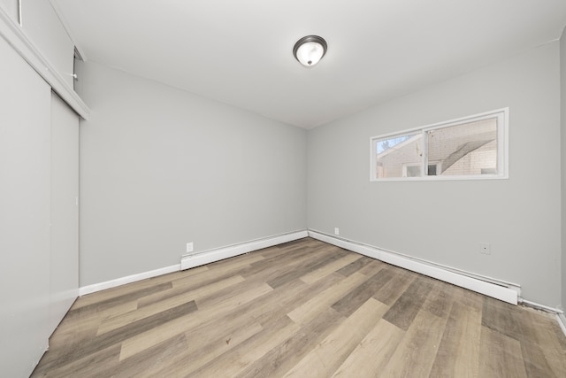 unfurnished bedroom featuring light hardwood / wood-style flooring, a closet, and a baseboard radiator