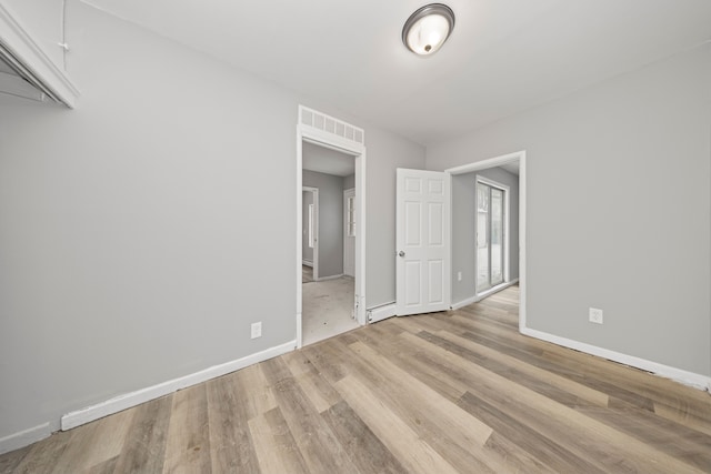 unfurnished bedroom with light hardwood / wood-style floors and a baseboard radiator