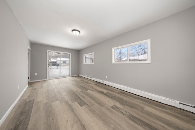 unfurnished room featuring baseboard heating and light wood-type flooring