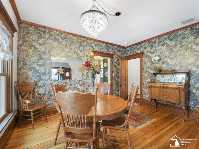 dining room featuring light hardwood / wood-style flooring, ornamental molding, and an inviting chandelier