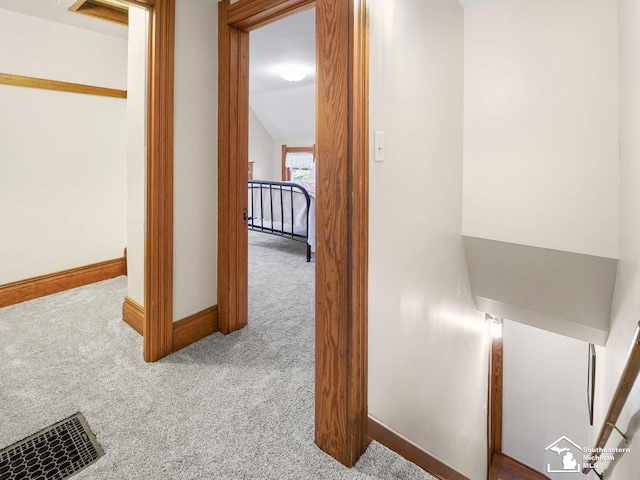 hallway featuring light colored carpet and lofted ceiling