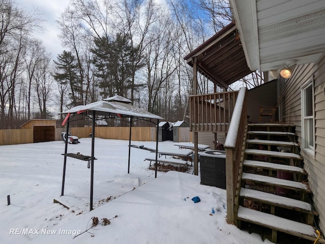 yard covered in snow featuring central AC unit and a storage unit