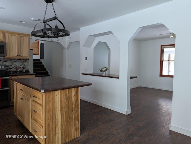 kitchen featuring backsplash, pendant lighting, a center island, black electric range oven, and dark wood-type flooring