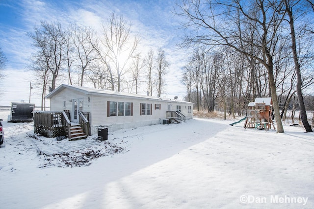 snow covered back of property with a playground