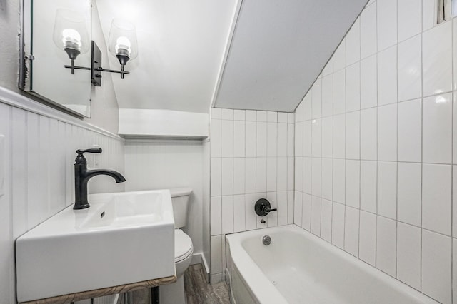 bathroom with toilet, lofted ceiling, hardwood / wood-style flooring, and sink