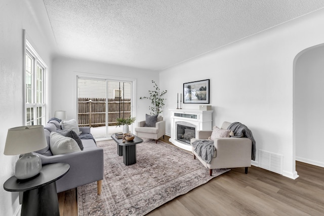 living room with a textured ceiling, a fireplace, and hardwood / wood-style floors